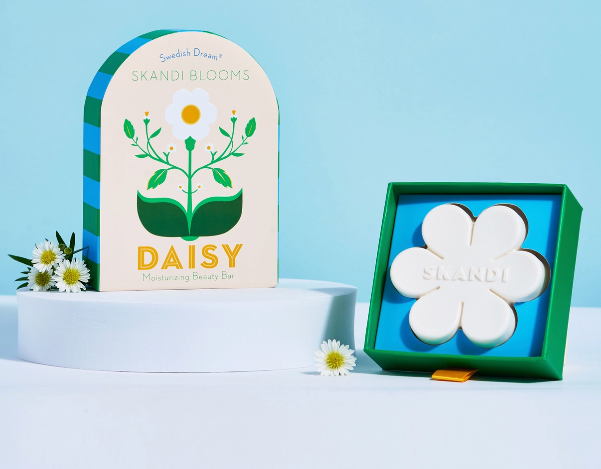 Skandi Blooms daisy product packaging with white bar of hydrating soap on a light blue background