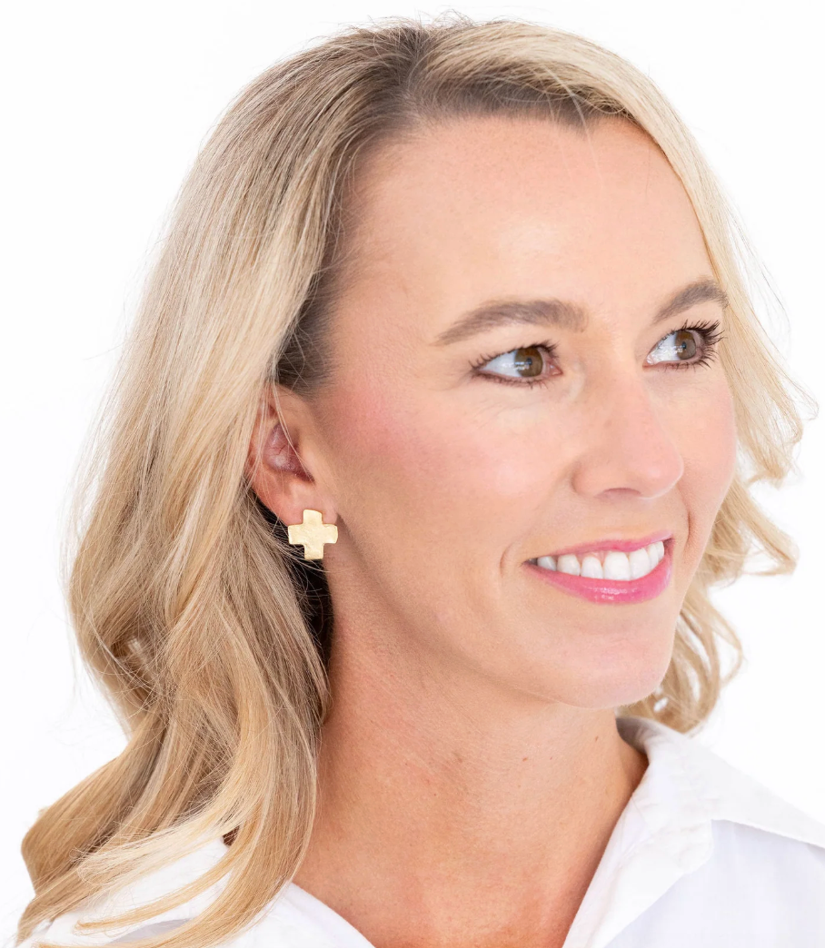 Woman wearing a pair of Susan Shaw gold cross mini earring on a white background