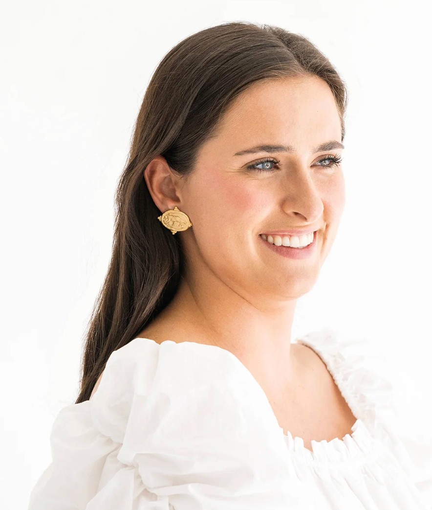 Woman wearing gold tiger stud oval Susan Shaw earrings with a white background