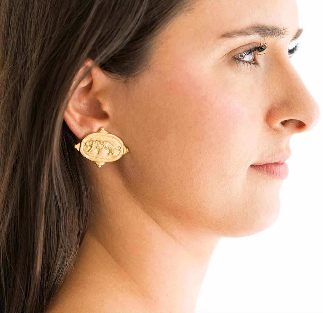 Close-up of a woman wearing a gold susan Shaw tiger stud earring with a white background