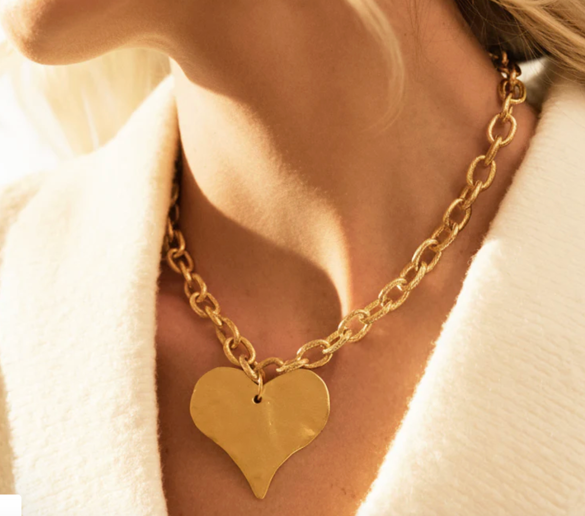 Susan Shaw close up of Gold heart-shaped necklace on a person wearing a white sweater