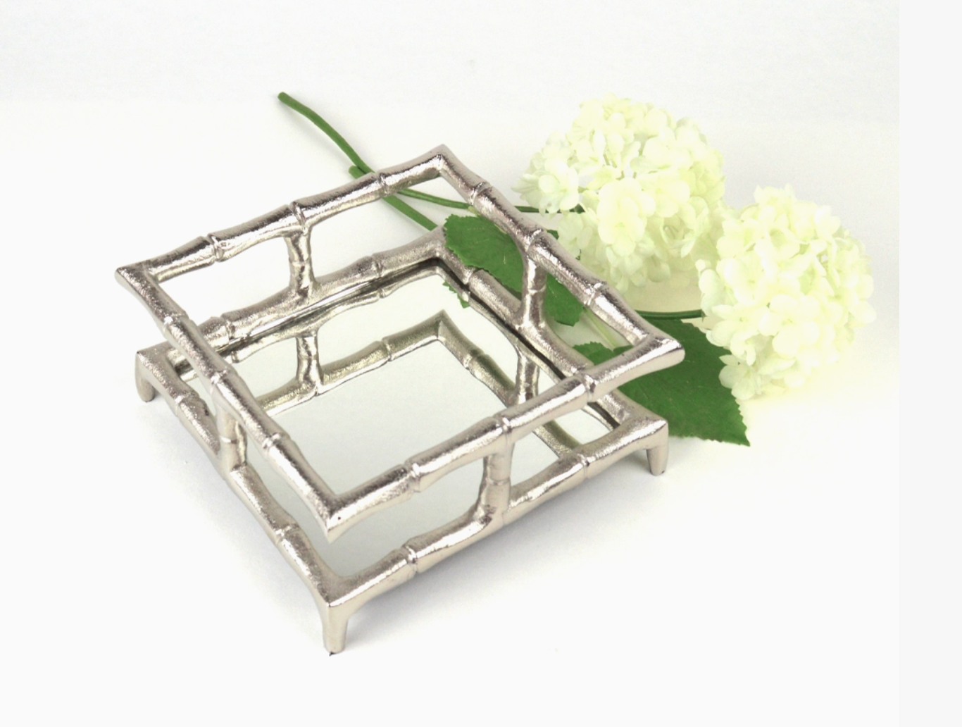  Oak Lane Brand silver bamboo cocktail napkin holder with mirrored bottom on a white background with a white flower