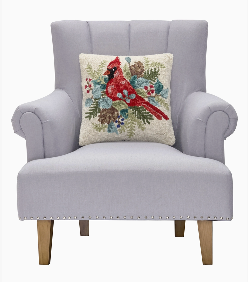 Gray armchair with a Peking Handicrafts Brand Decorative pillow with a red cardinal bird surrounded by foliage and berries on a white backgroundd