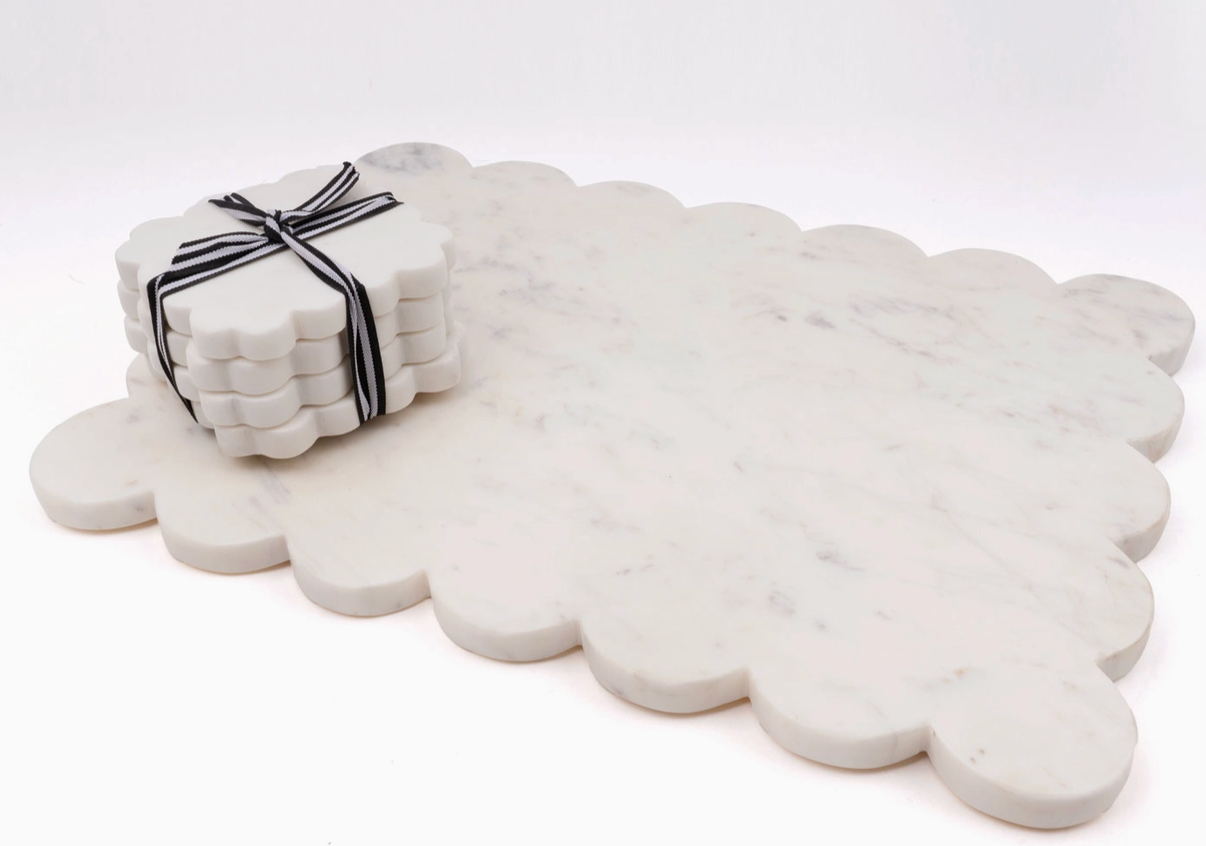 Four 8 Oak Lane brand scalloped marble coasters on wrapped in black and white ribbon on a scalloped marble board.
