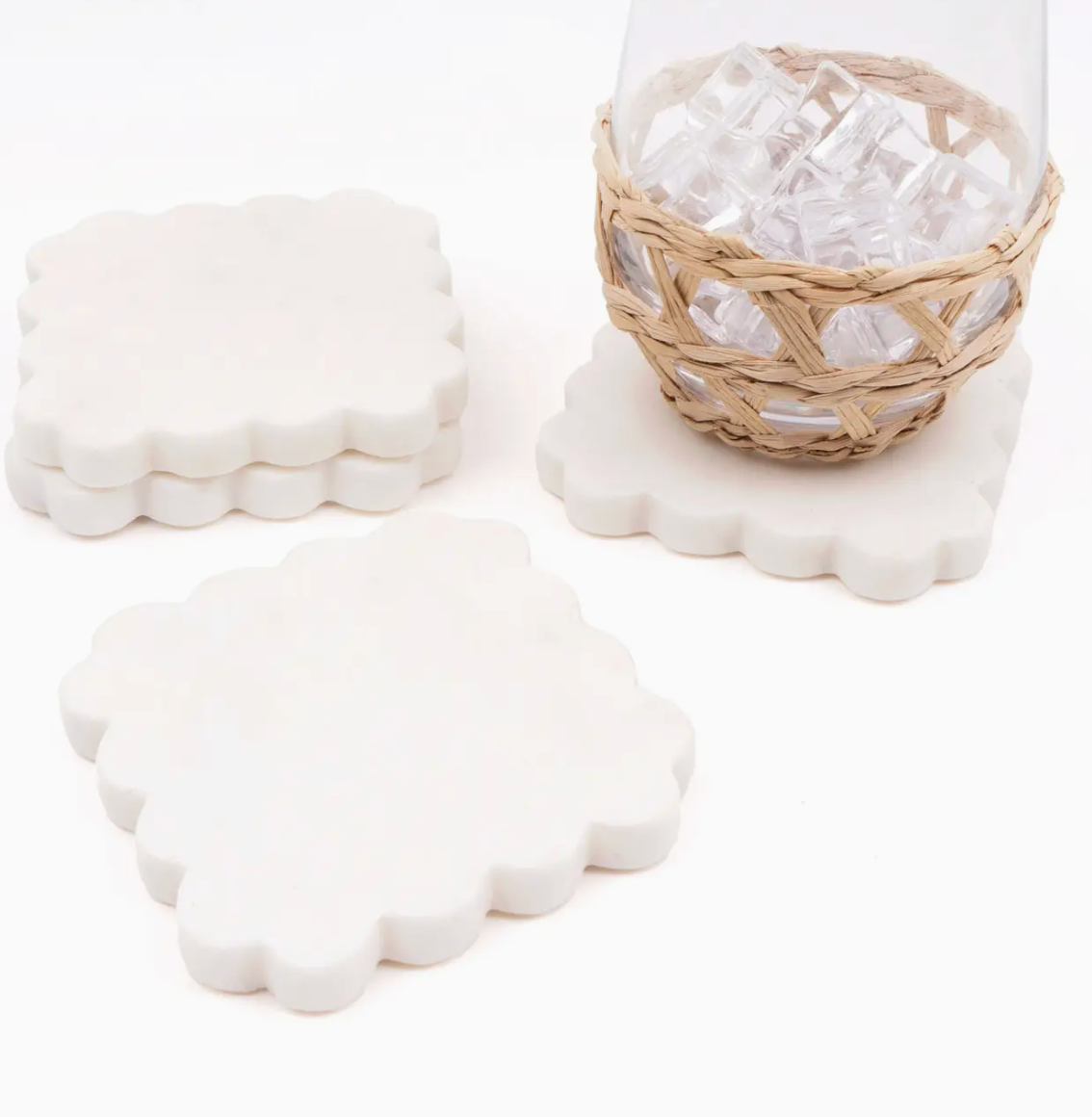 Four 8 Oak Lane brand scalloped marble coasters with a glass on it on white background