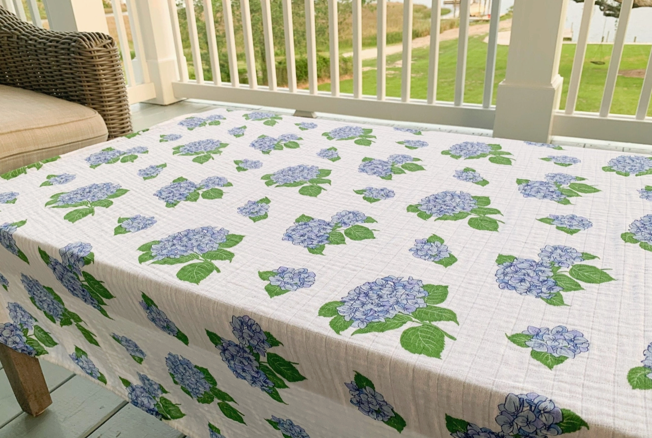 Little Hometown swaddle blanket with blue hydrangea pattern on a table outdoors