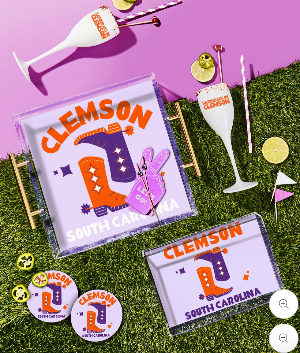 Clemson-themed glassware and decor items on a grassy surface with a purple background.