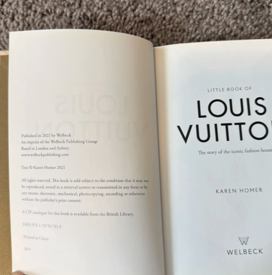 An open book showing the title page for 'Little Book of Louis Vuitton' by Karen Homer, with visible Welbeck publisher text on the left page and a white right page.