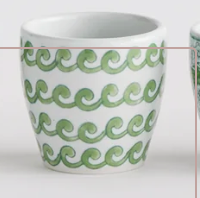 A white Napa Home and Garden ceramic cup with a repeating green wavy pattern, shown against a plain white background.