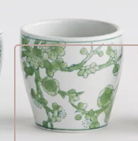 A Napa Home and Garden Brand white ceramic cup decorated with a green floral and branch pattern, shown against a plain white background.