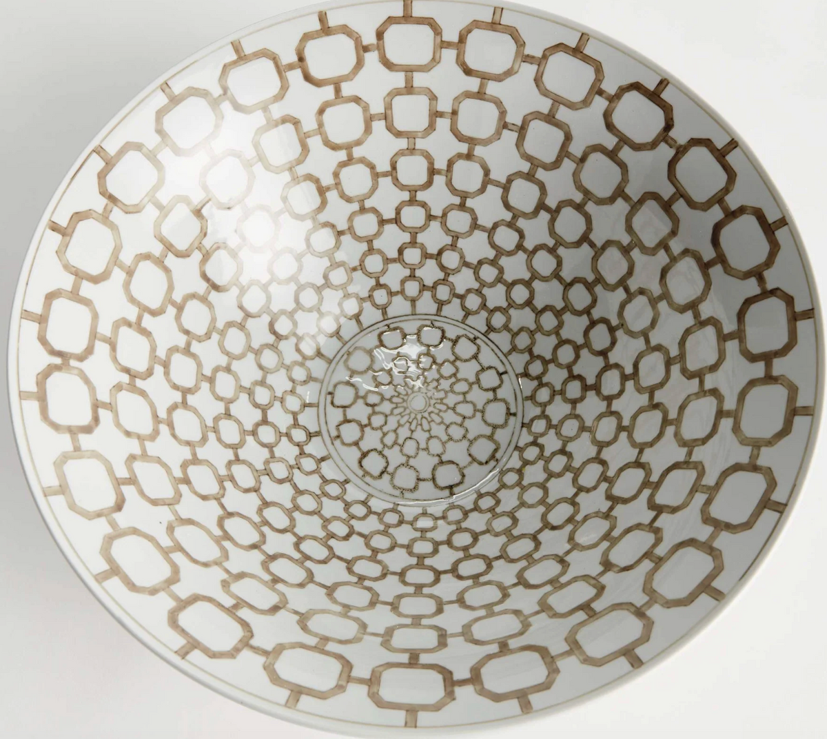 A white ceramic bowl viewed from directly above, featuring an intricate geometric pattern of interlocking hexagons and octagons in a warm brown tone.