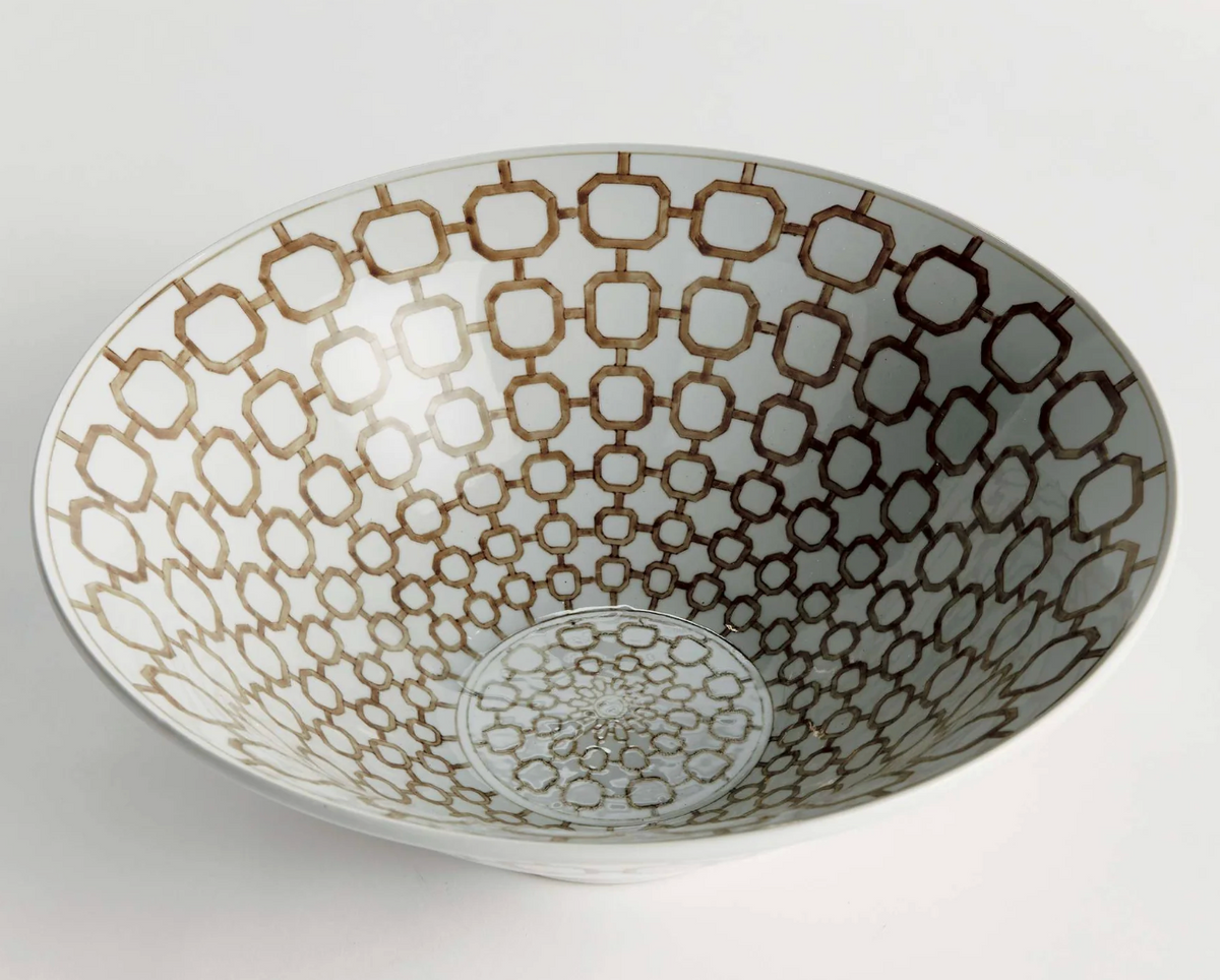 A white ceramic bowl featuring an intricate brown geometric trellis pattern printed on the inside, photographed from a top-down angle on a light gray background.
