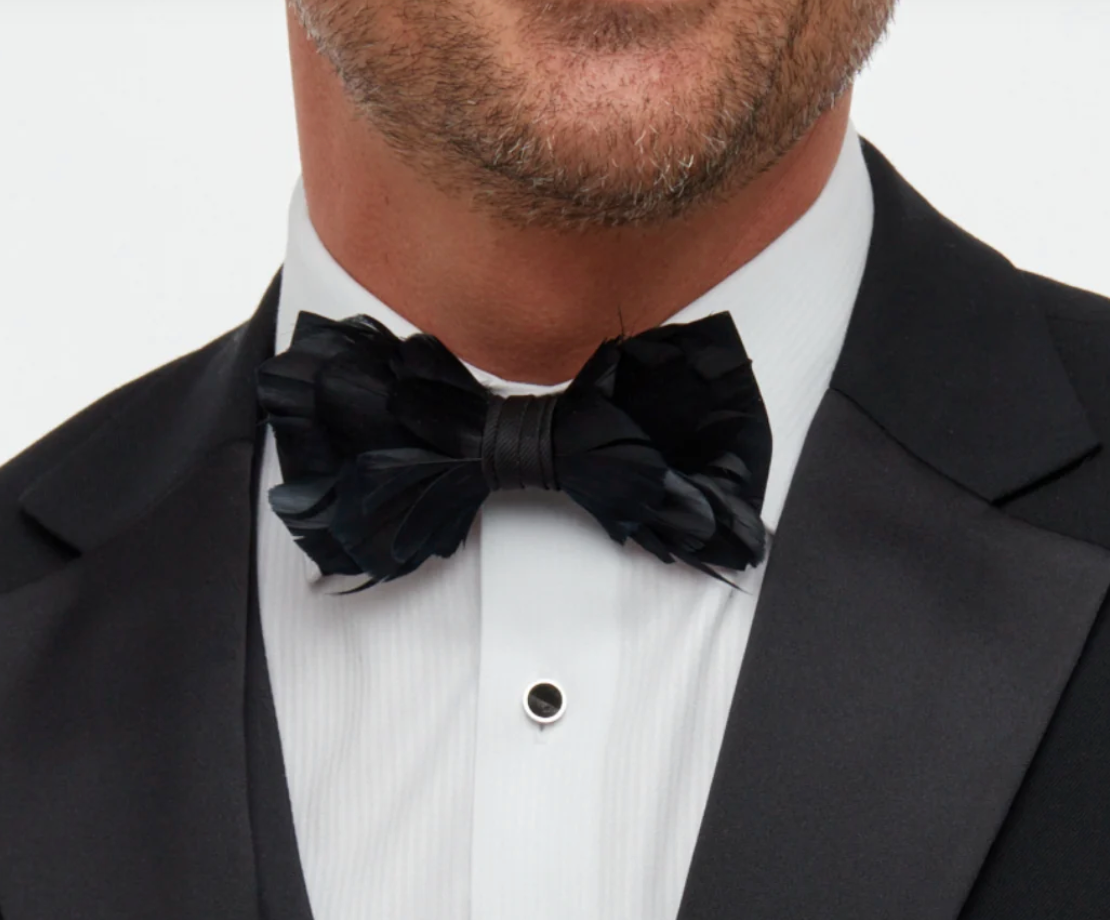 Brackish Brand black Goose Feather Bow Tie with black fabric wrap on a man wearing a white shirt and black  jacket showing partial neck and chin