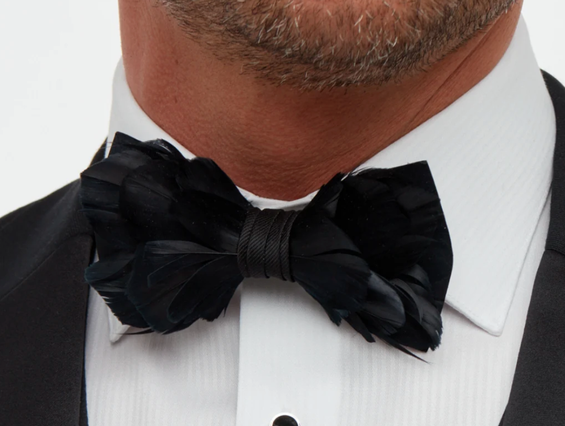 Brackish Brand black Goose Feather Bow Tie with black fabric wrap on a man wearing a white shirt and black  jacket showing partial neck and chin