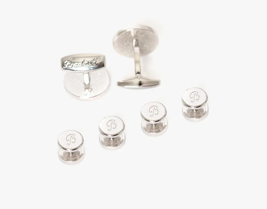 backside of cuff link set showing 4 silver studs and 2 cuff links with brackish engraved on them on white background