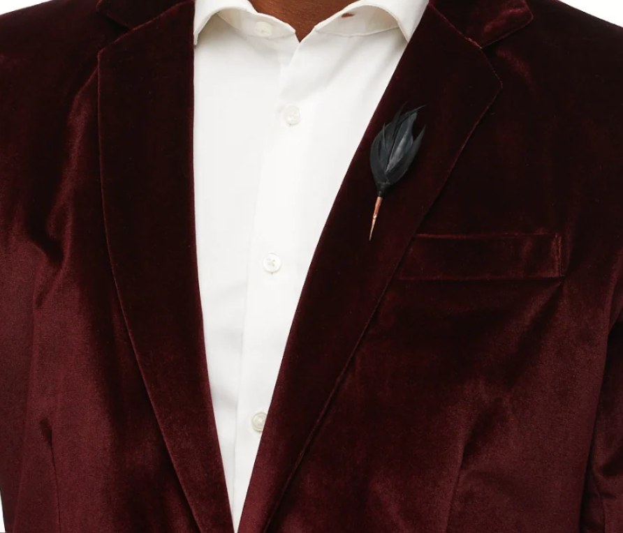 Brackish lapel pin of black feathers on a dark red suit lapel with white shirt
