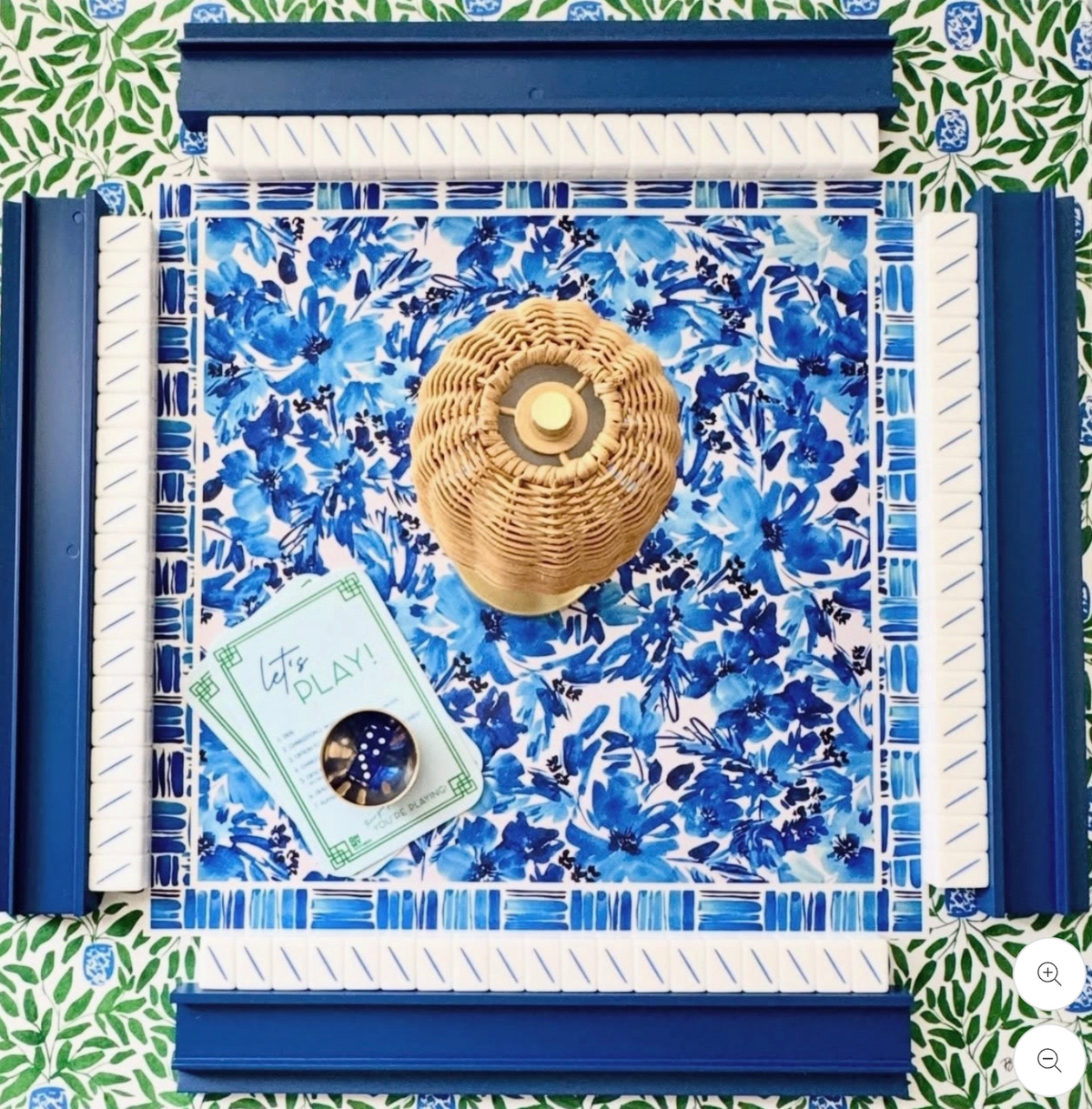 Mahjong Mat from Britt Mills "Royal Blooms" blue and white flowered mahjong mat withrattan basket and cards on top. Green flowered border and navy racks
