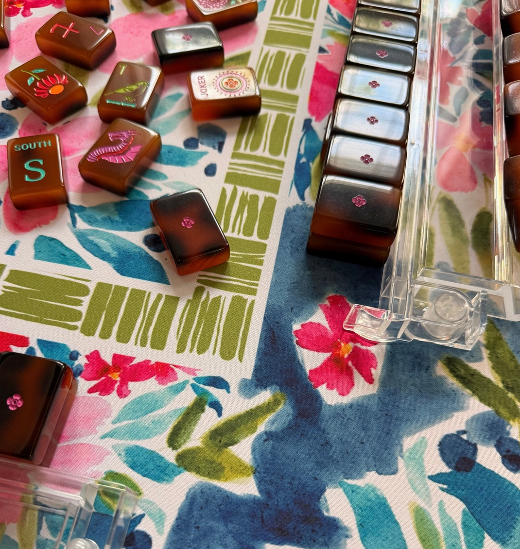 Close up of mahjong brown tiles on Britt Mills brand Aria mat with watercolor flowers and green border
