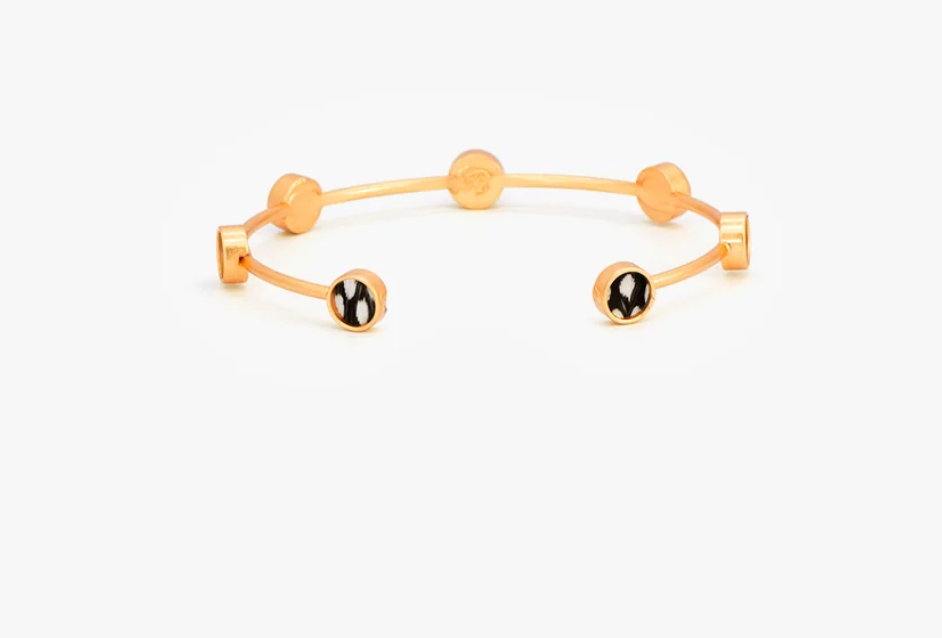 Brackish brand Gold cuff bracelet with black and white feather round insets on white background
