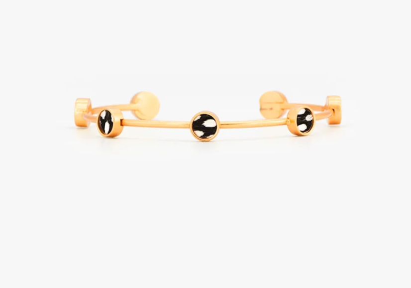 Brackish brand Gold cuff bracelet with black and white feather round insets on white background