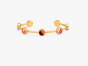 gold cuff bracelet from Brackish brand with 7 gold bezels with pink and dark feathers on white background