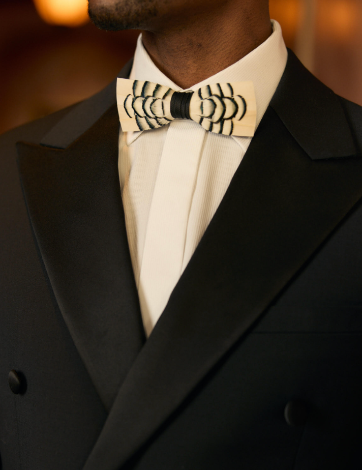 Cream and black Brackish feather bow tie worn with a white dress shirt and dark formal jacket