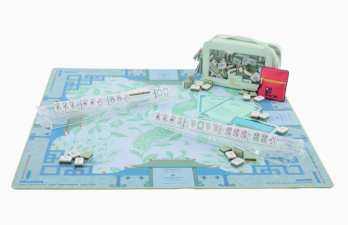 Oh My Mahjong Isla peacock mat styled with clear racks, mahjong tiles, reference cards, and a pale green tile bag.