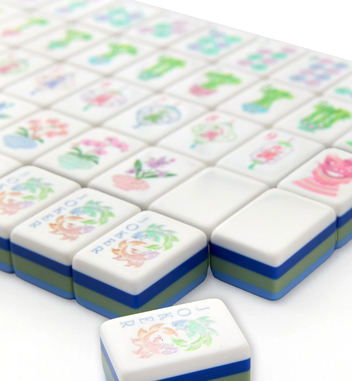 Close-up of Oh My Mahjong Moonlight tiles with orchid and floral Joker designs and layered blue and green edges.