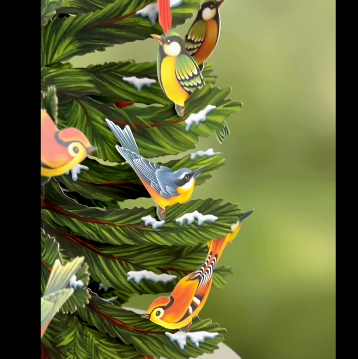 section of paper tree with colorful birds and snow on branches on a green background