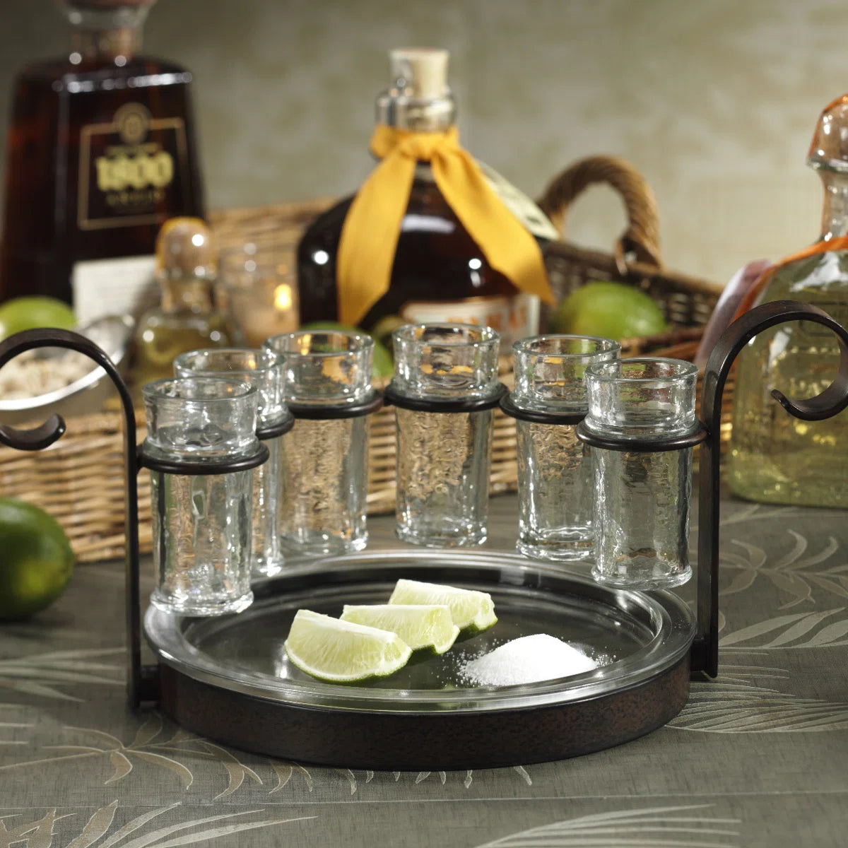 Set of Zodax brand shot glasses on a tray with limes and sugar, surrounded by bottles in a casual setting.
