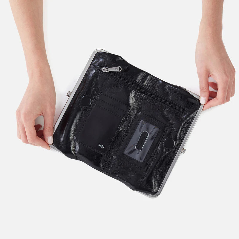 Black leather clutch bag held by a person on a white background