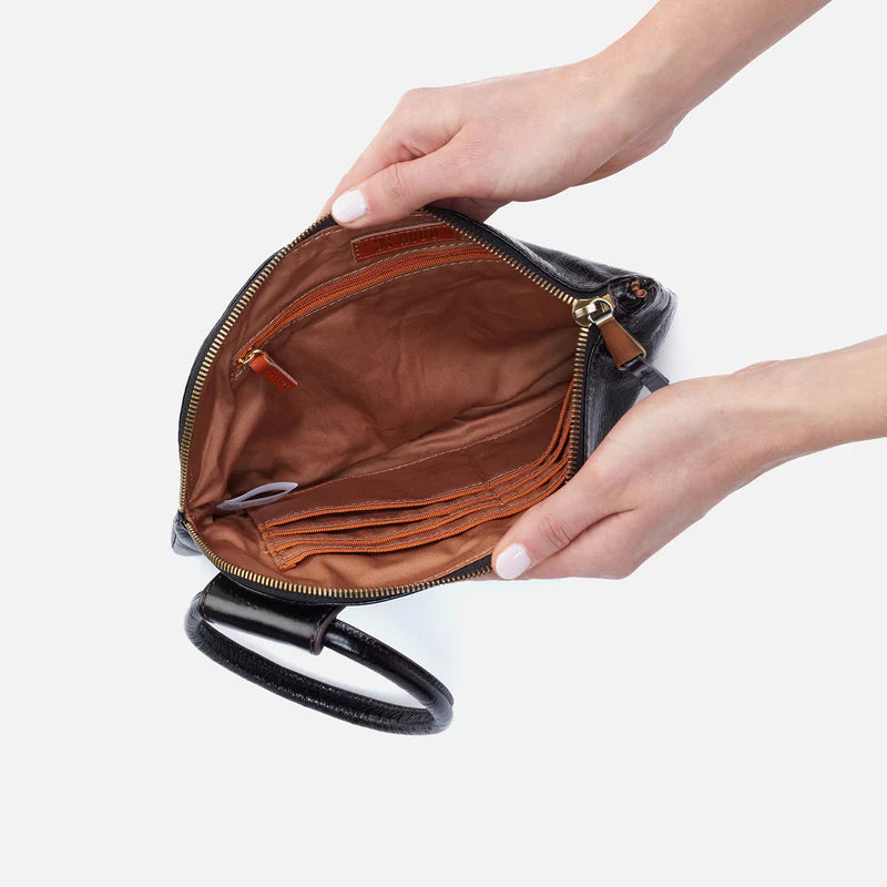Hand holding an open black leather clutch bag with a white background