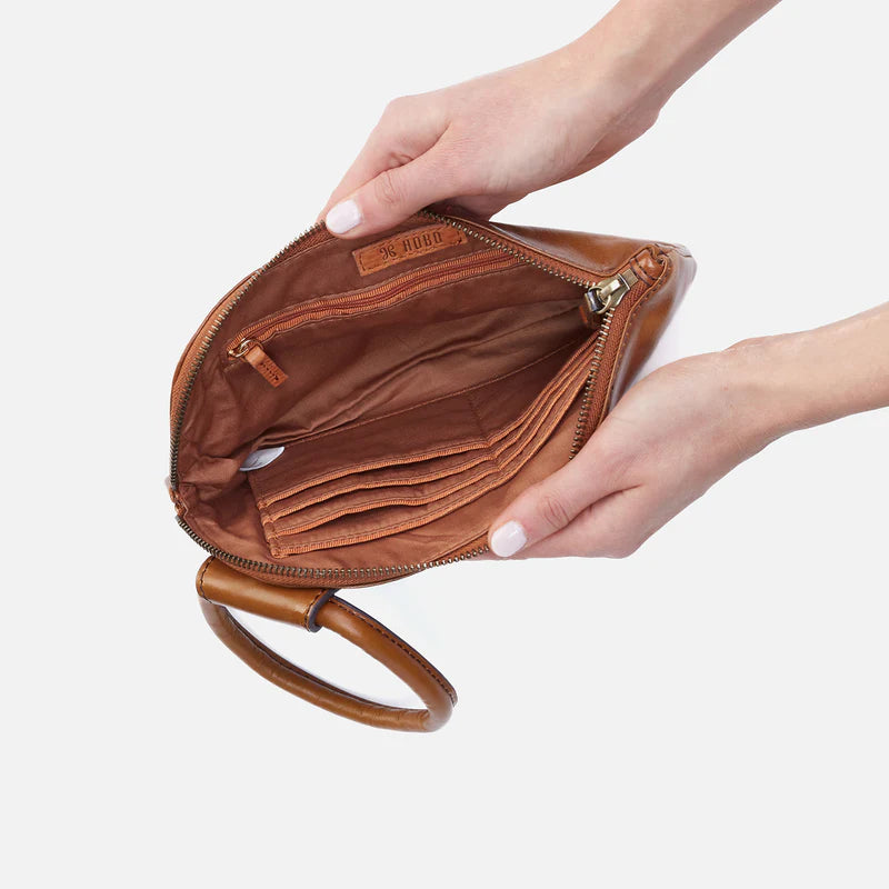 Brown leather clutch held by a hand on a white background