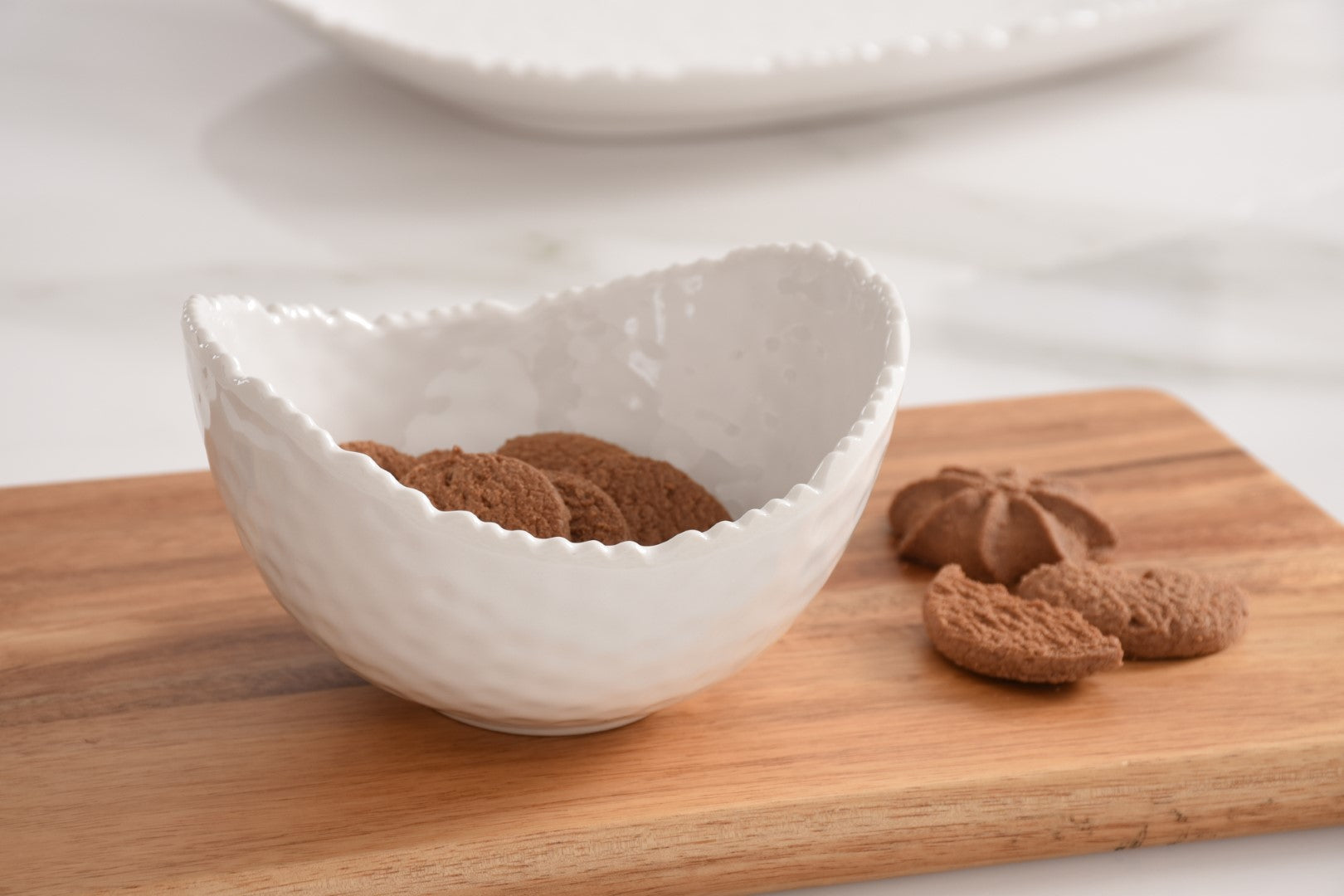 White textured Pampa bay melamine bowl with cookies on a wooden cutting board