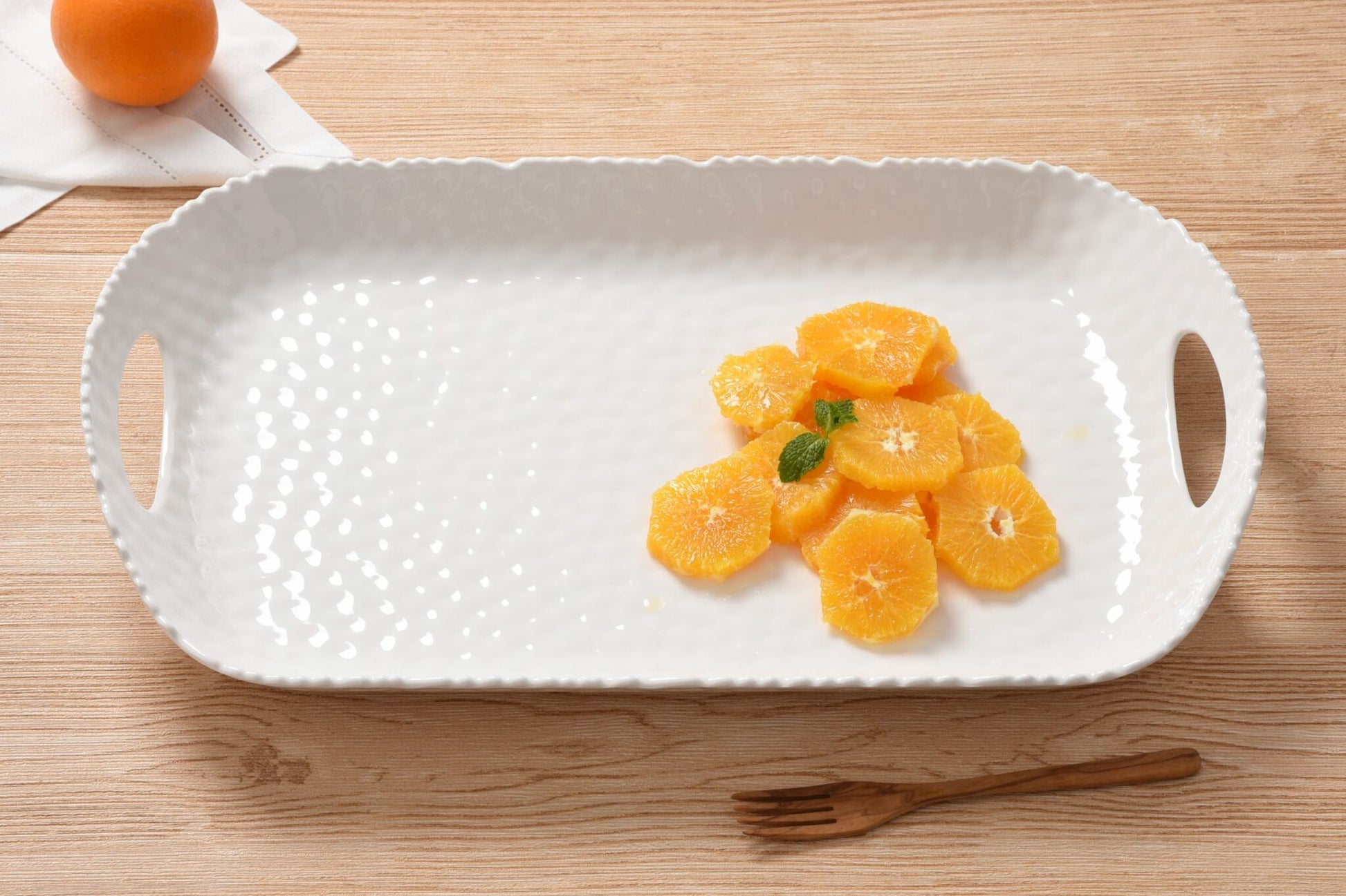 White Pampa bay melamine textured serving tray with sliced oranges on a wooden surface