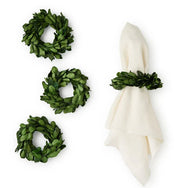 Set of three green wreath napkin rings with a white napkin on a white background