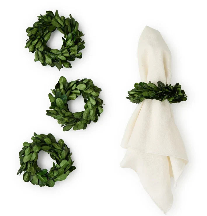 Set of three green wreath napkin rings with a white napkin on a white background