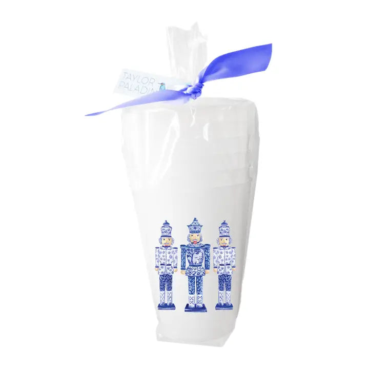 White cups with blue nutcracker design in a clear package with a blue ribbon on a white background