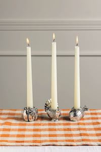 Seasonal - Taper Holder - Silver Acorn and other silver varieties with taper candles burning.  Sitting on orange plaid tablecloth 