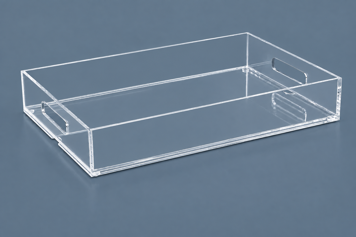 Clear rectangular acrylic tray with raised sides and cutout handles, shown at an angle on a  gray background.”