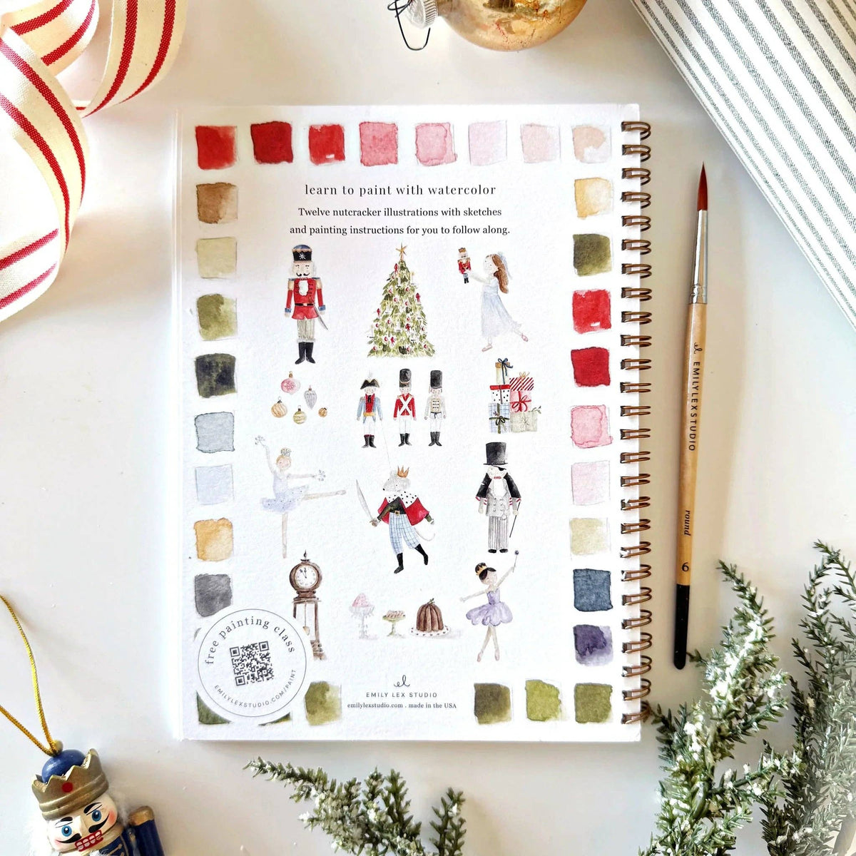 art book with watercolor illustrations on a decorative surface with Christmas decorations.