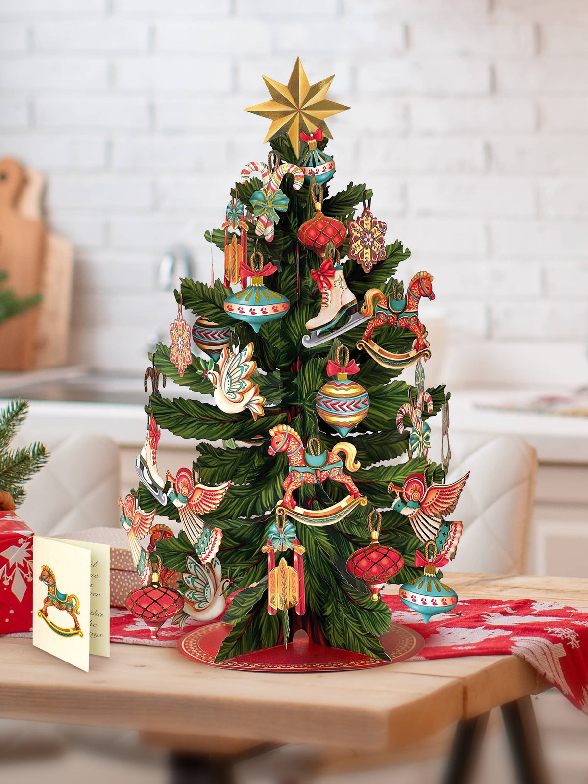 Decorative freshcut Paper brand pop up Christmas tree with colorful ornaments on a wooden table.