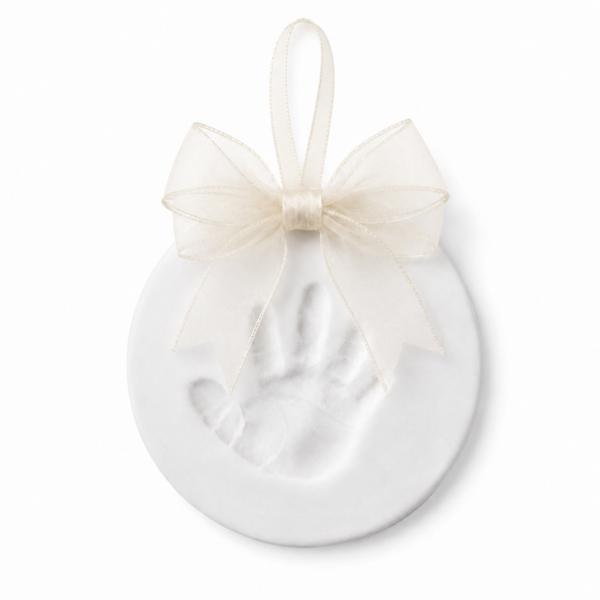 A white circular keepsake ornament featuring an embossed baby handprint, decorated with a sheer ivory ribbon bow and hanging loop, shown on a clean white background.