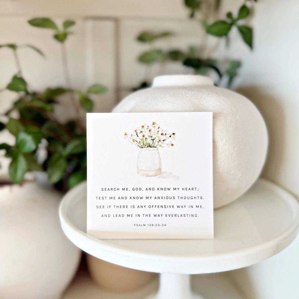 Card with floral design and text on a white surface with plants in the background