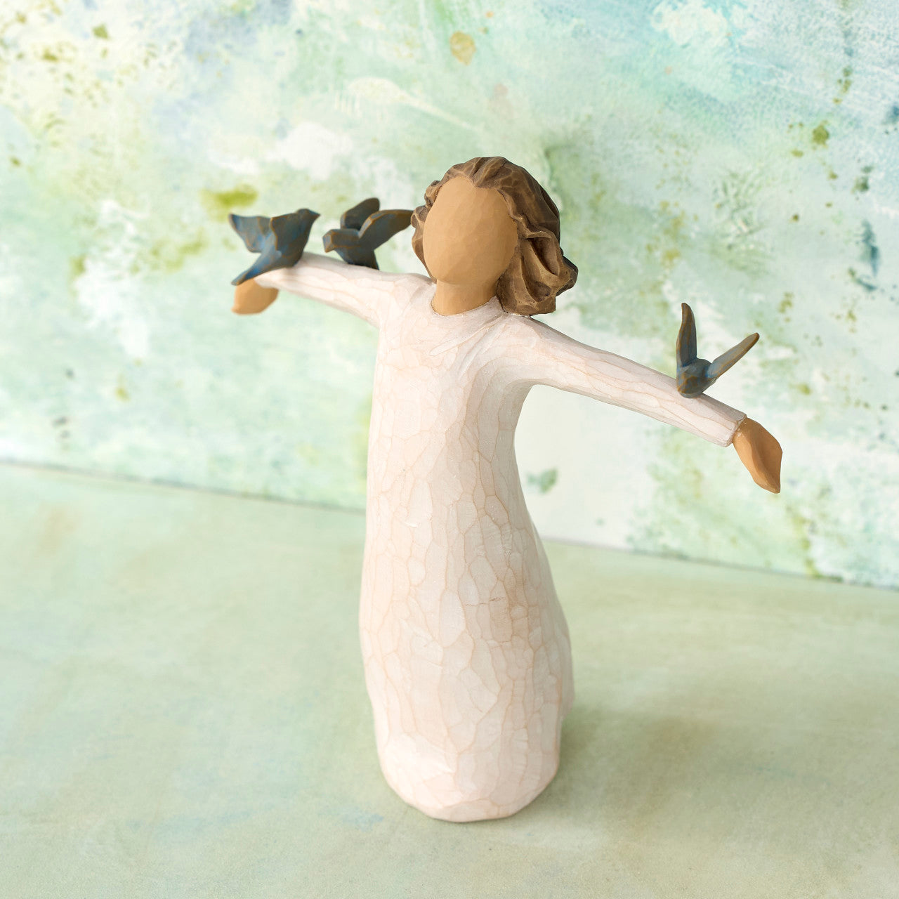Decorative figurine of a woman with birds on her hands against a light background