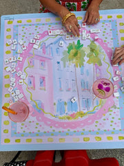 Mahjong game mat with colorful design and hands playing on a pink and blue themed board