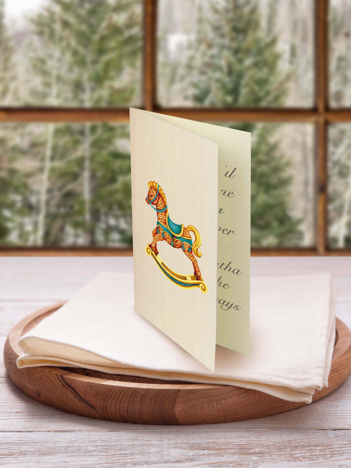 Greeting card with a colorful rocking horse design on a wooden tray with a window view in the background.