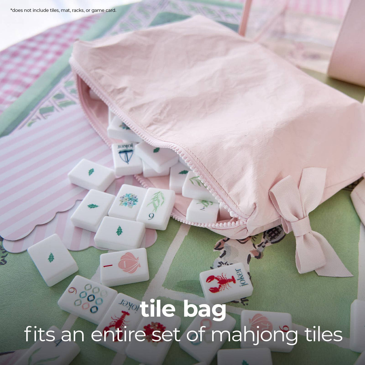 A light pink fabric zippered tile bag with ribbon bows, shown with white mahjong tiles spilling out onto a pastel patterned surface. Text on the image reads 'tile bag fits an entire set of mahjong tiles'.