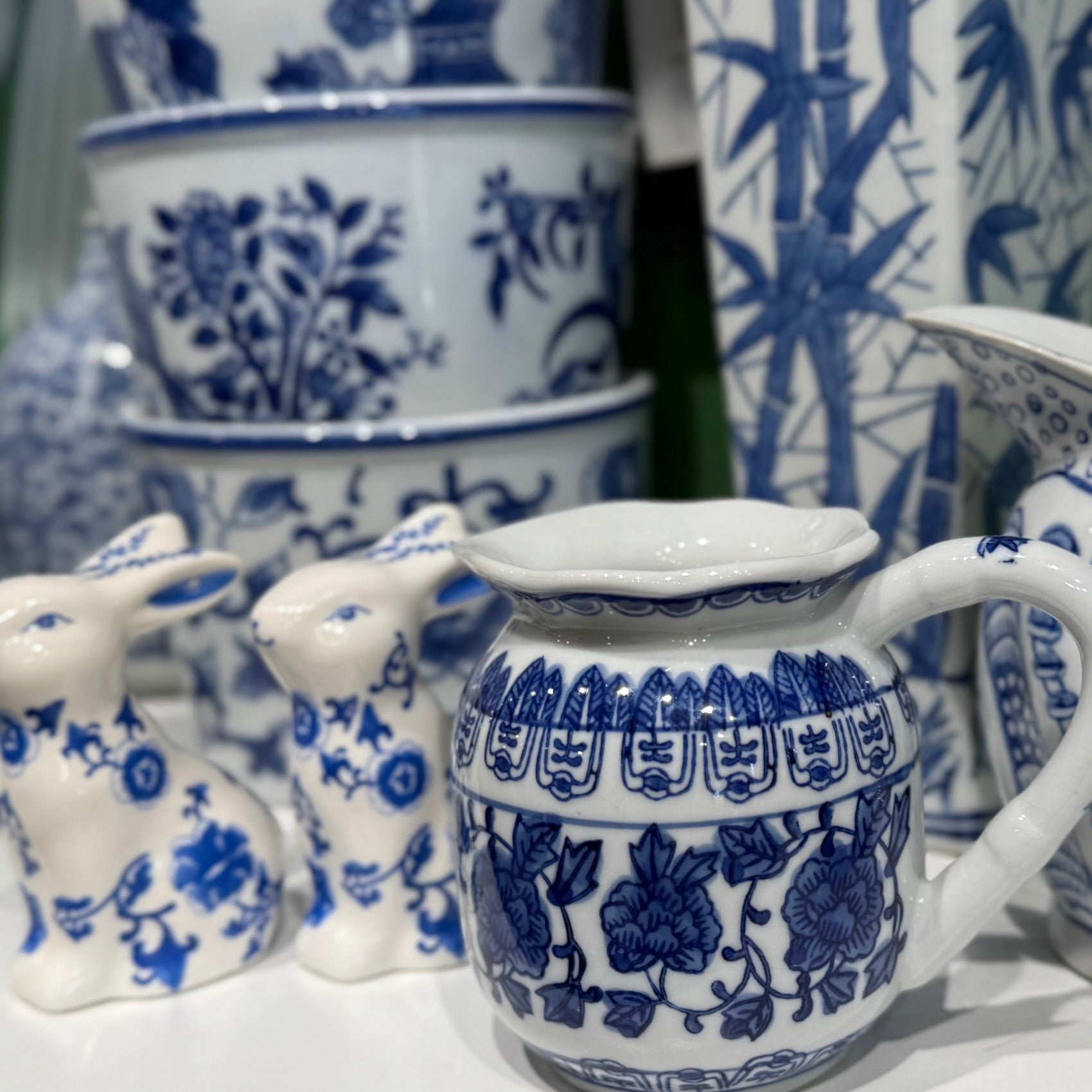Blue and white ceramic items including a pitcher and rabbit figurine on a white surface.