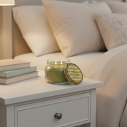 Tyler Candle Company Diva 11 oz two-wick scented candle with green wax and decorative leopard-print lid styled on a bedside table with cream bedding and books